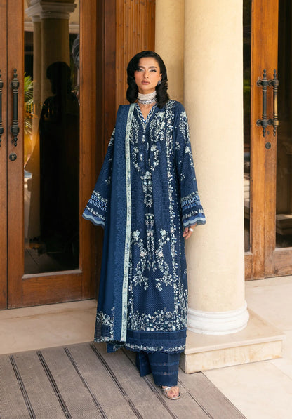 Woman wearing a blue embroidered traditional outfit standing in front of a building entrance with ELAF LUXURY WINTER