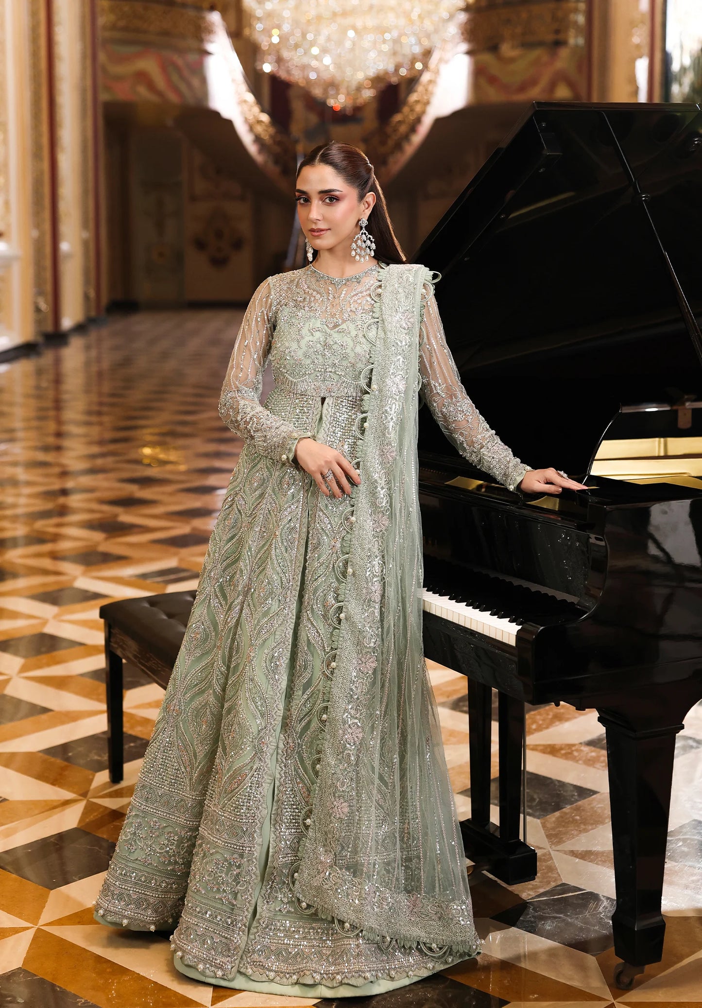 Woman in a traditional outfit standing next to a grand piano in an elegant interior setting.