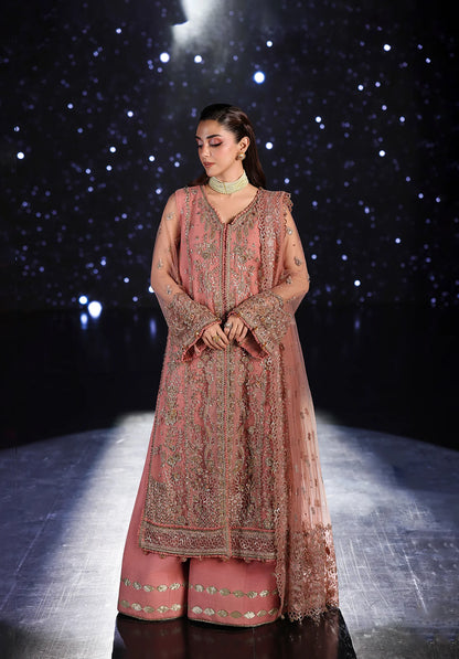 Woman in a traditional pink embroidered outfit on a dark background with star-like lights.