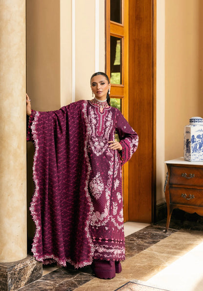Woman in a purple embroidered dress standing in an elegant interior setting.